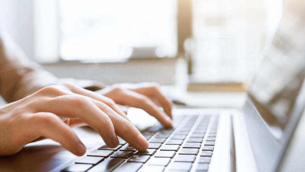 Laptoptastatur Person tippt auf eine Tastatur Mann sieht die Finger als Nahaufnahme.